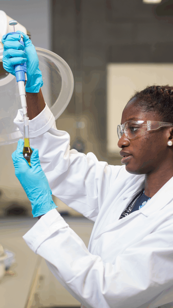 University of limerick student in white lab coat using a pipette in a laboratory
